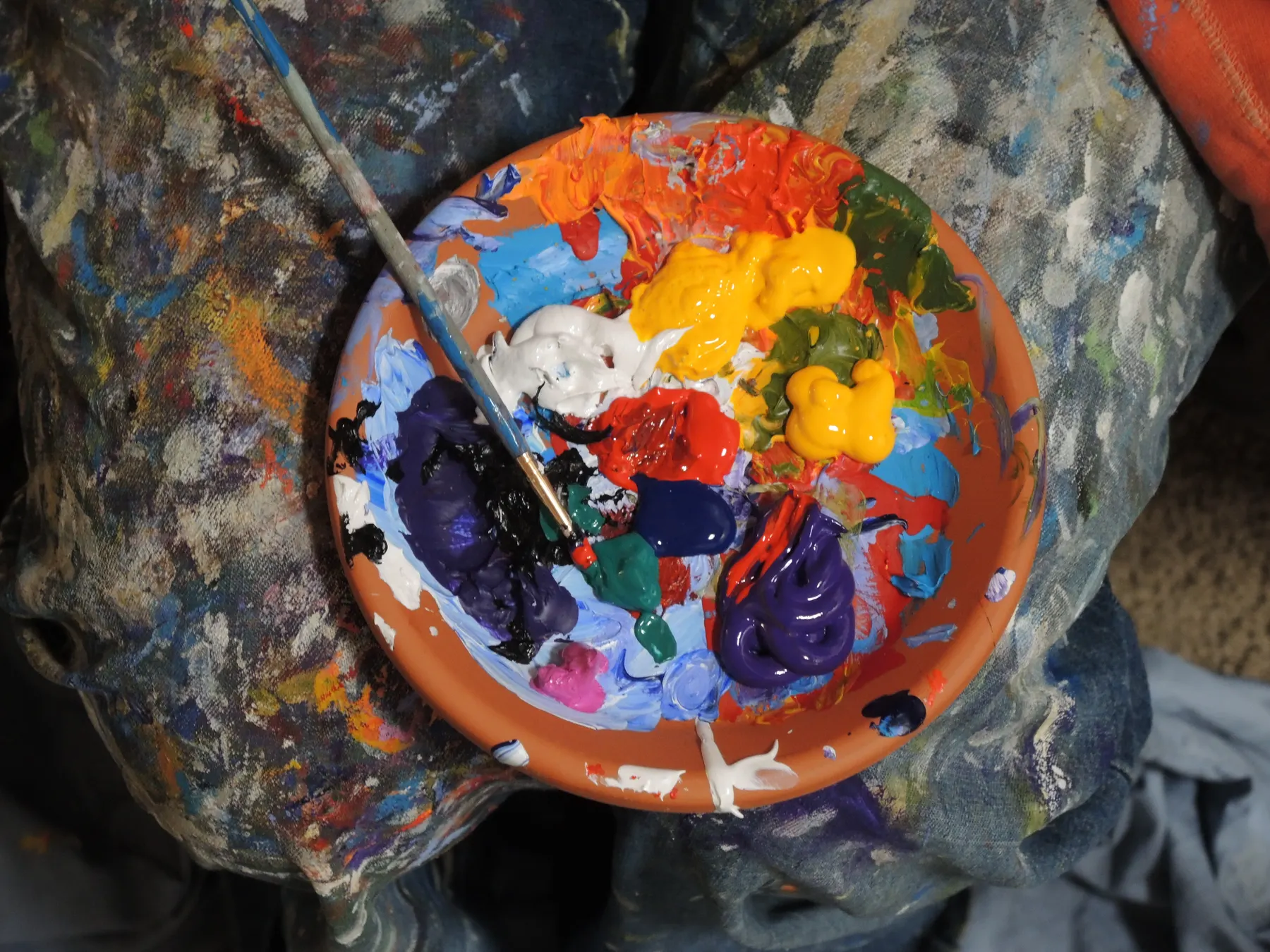 Artist palette loaded with fresh blobs of oil paint and a used brush